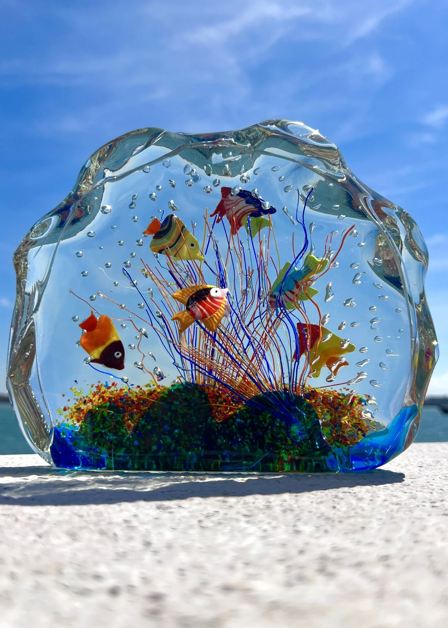 Hands holding a small Murano glass piece with label