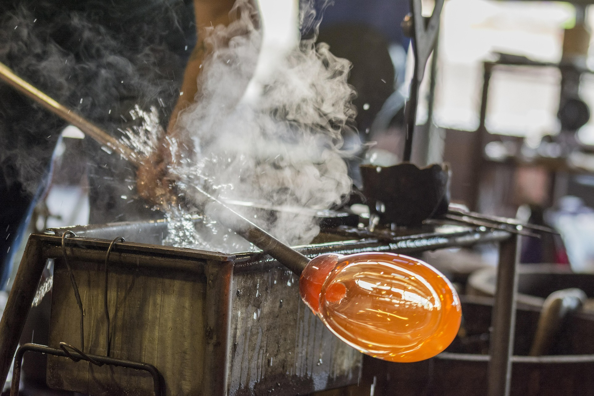 Glass master shaping a vessel at the bench in a Murano furnace workshop